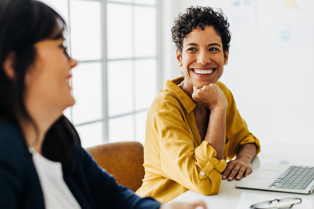 Två revisorer vid ett mötesbord. De pratar med varandra och är glada.