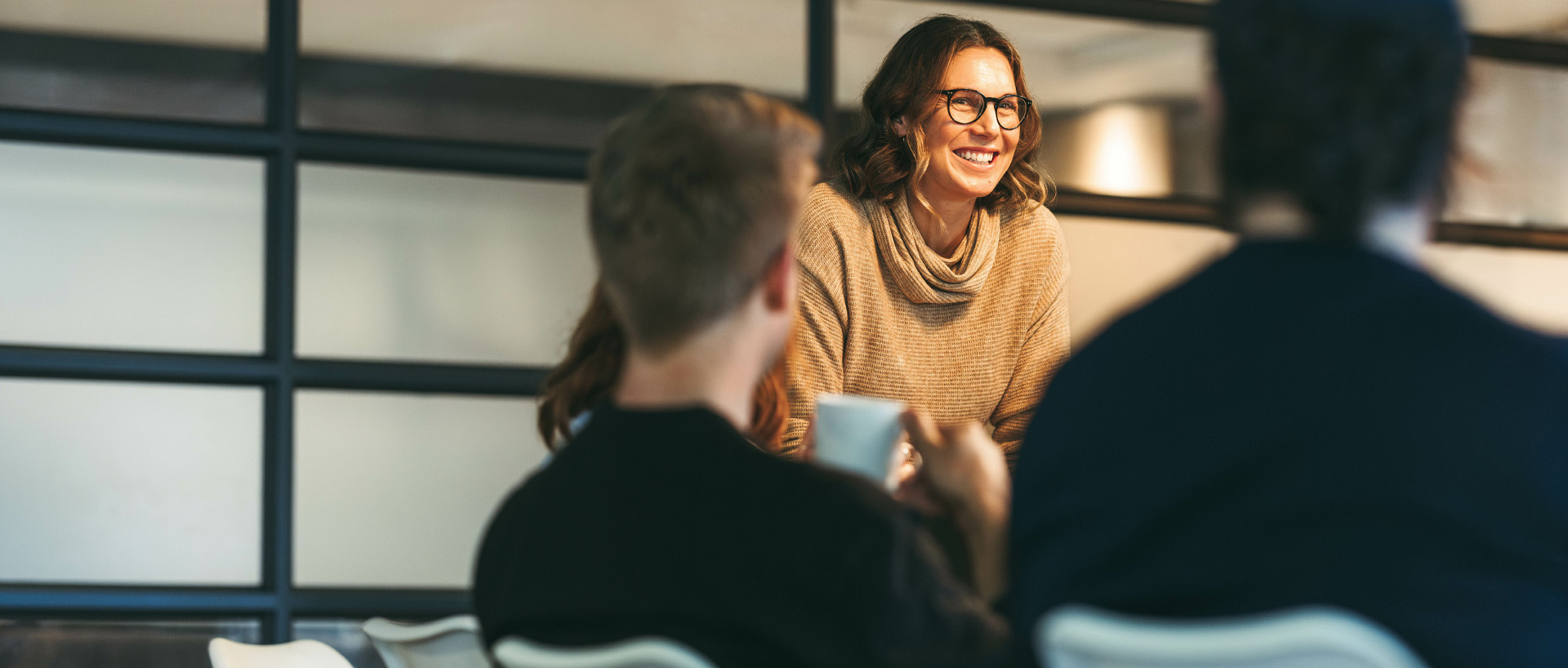 Några revisorer i ett mötesrum. I fokus en kvinna som står upp och ler mot oss.
