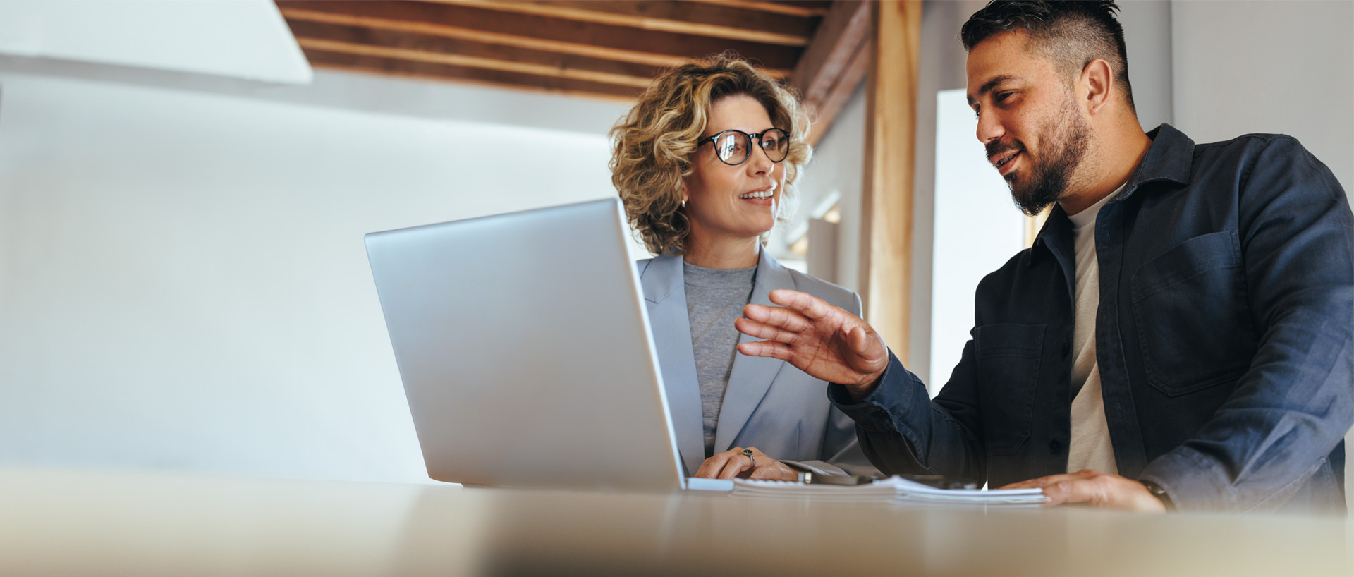 Två kommunala revisorer diskuterar ekonomi vid en laptop.
