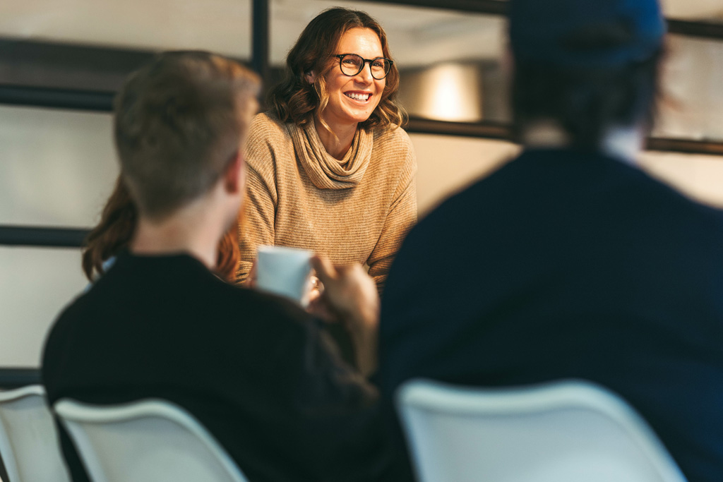 Några revisorer i ett mötesrum. I fokus en kvinna som står upp och ler mot oss.