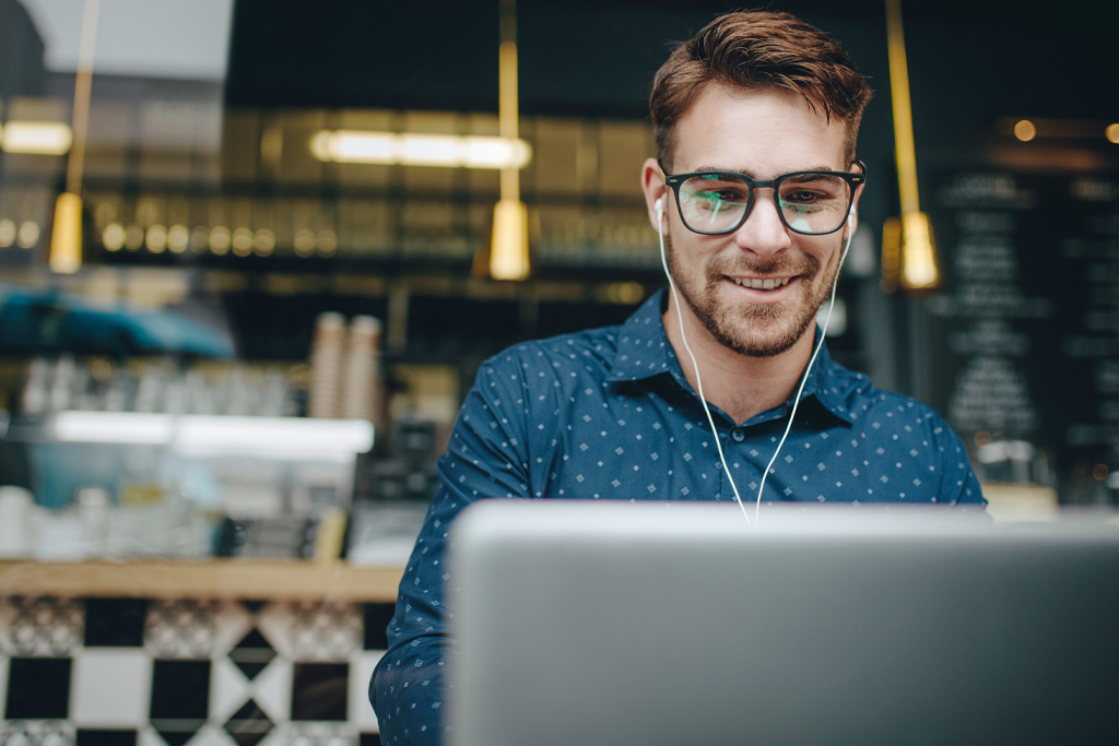 Ung man som jobbar som revisor sitter i ett café och arbetar.